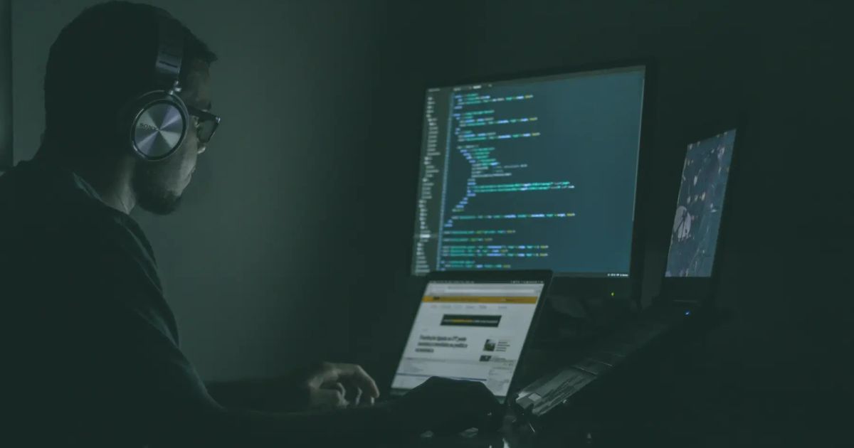 Developer working on code at night with headphones on