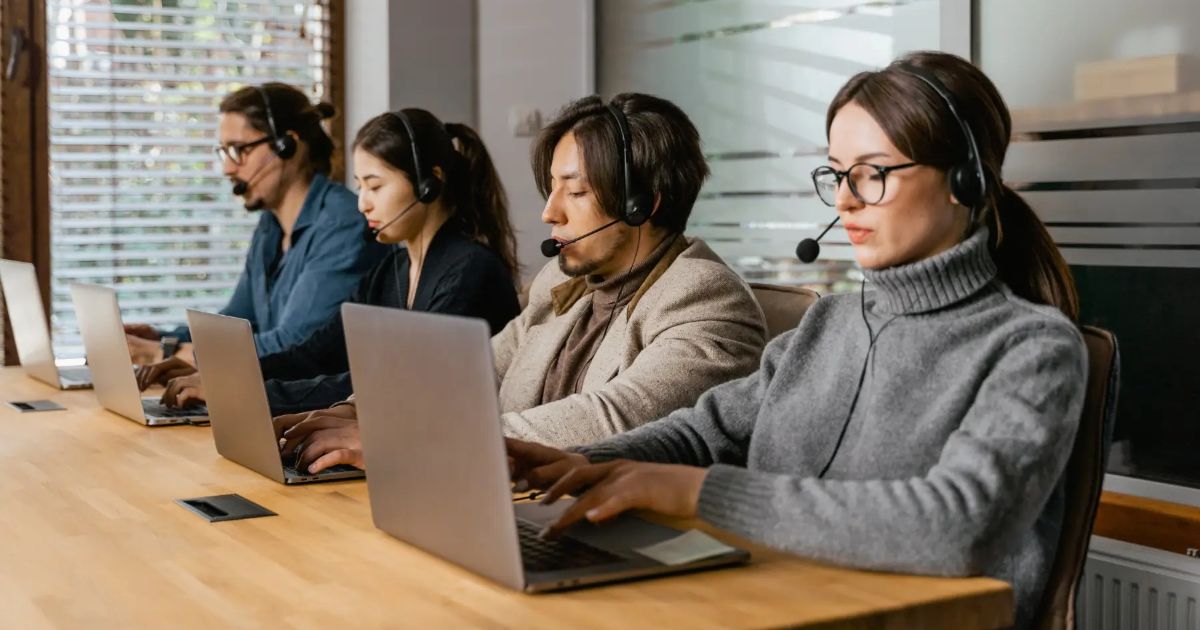Call centre team wearing headsets working on laptops